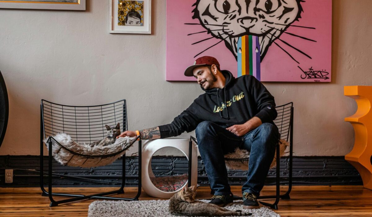 A man petting a cat in a trendy retail store.