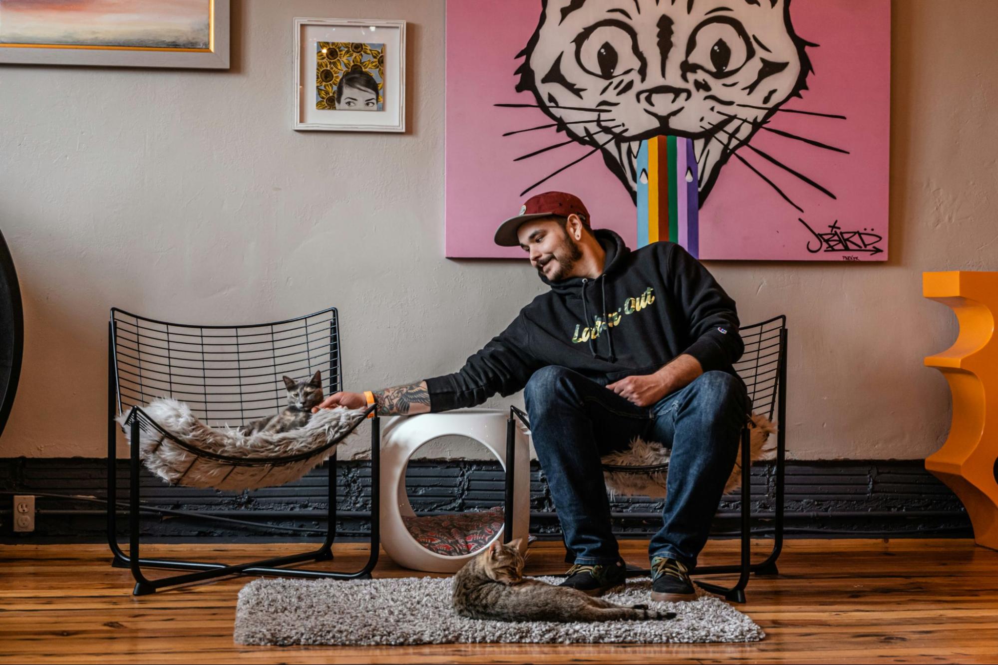 A man petting a cat in a trendy retail store.